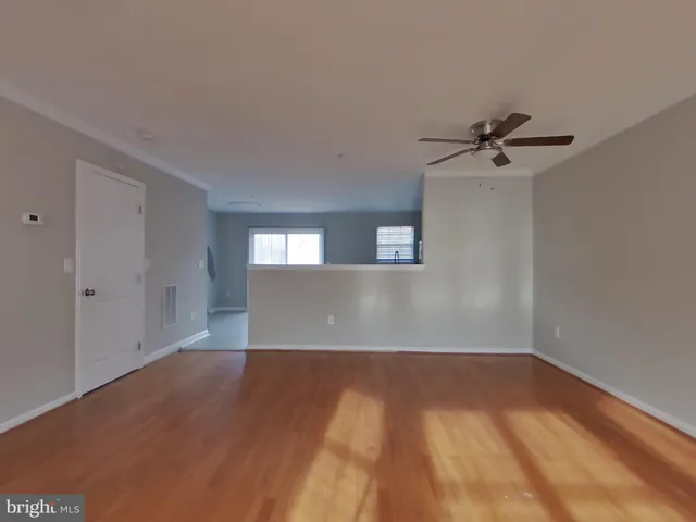 a view of a big room with wooden floor and windows