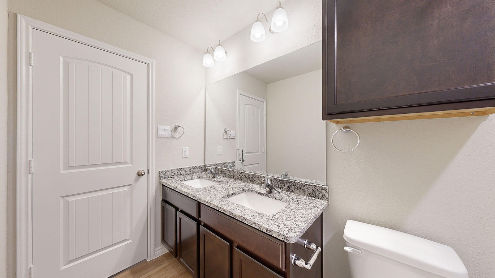243 Water Wl Road Burnet, TX 78611 - Photo 21 of 23 Bathroom featuring a double vanity with granite countertop, integrated sinks, dark wood-finish cabinetry, and wood-finish flooring