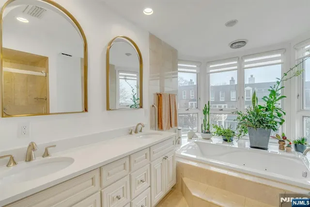 a bathroom with a tub a sink and a large mirror