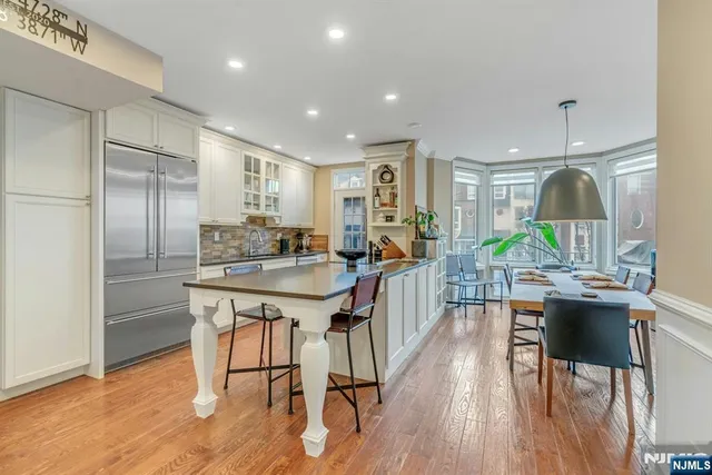 a kitchen with stainless steel appliances granite countertop a kitchen island hardwood floor sink stove dining table and chairs