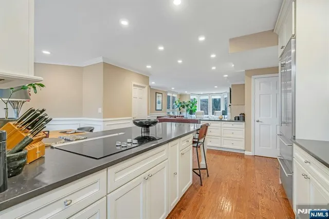 a kitchen with stainless steel appliances granite countertop a sink a stove a refrigerator and white cabinets with wooden floor