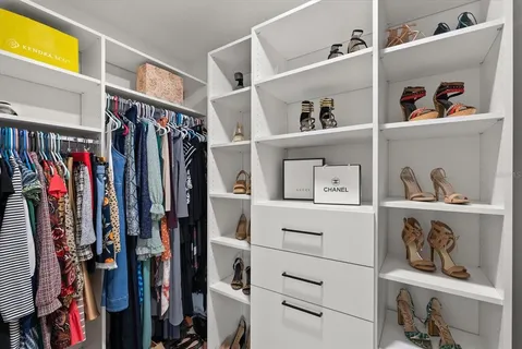 a view of walk in closet with clothes and shoes