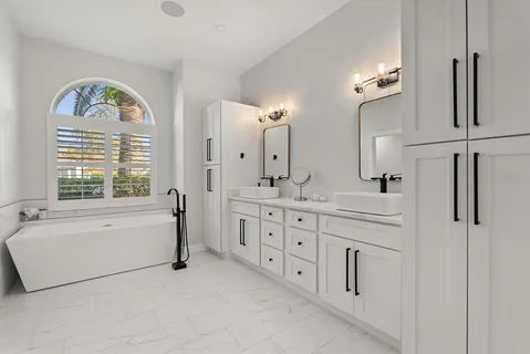 a bathroom with a double vanity sink a mirror a bathtub and window