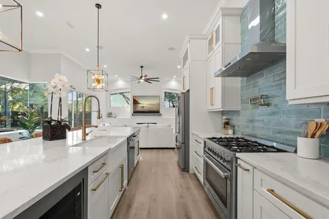 a kitchen with stainless steel appliances granite countertop a sink a stove and a wooden floors