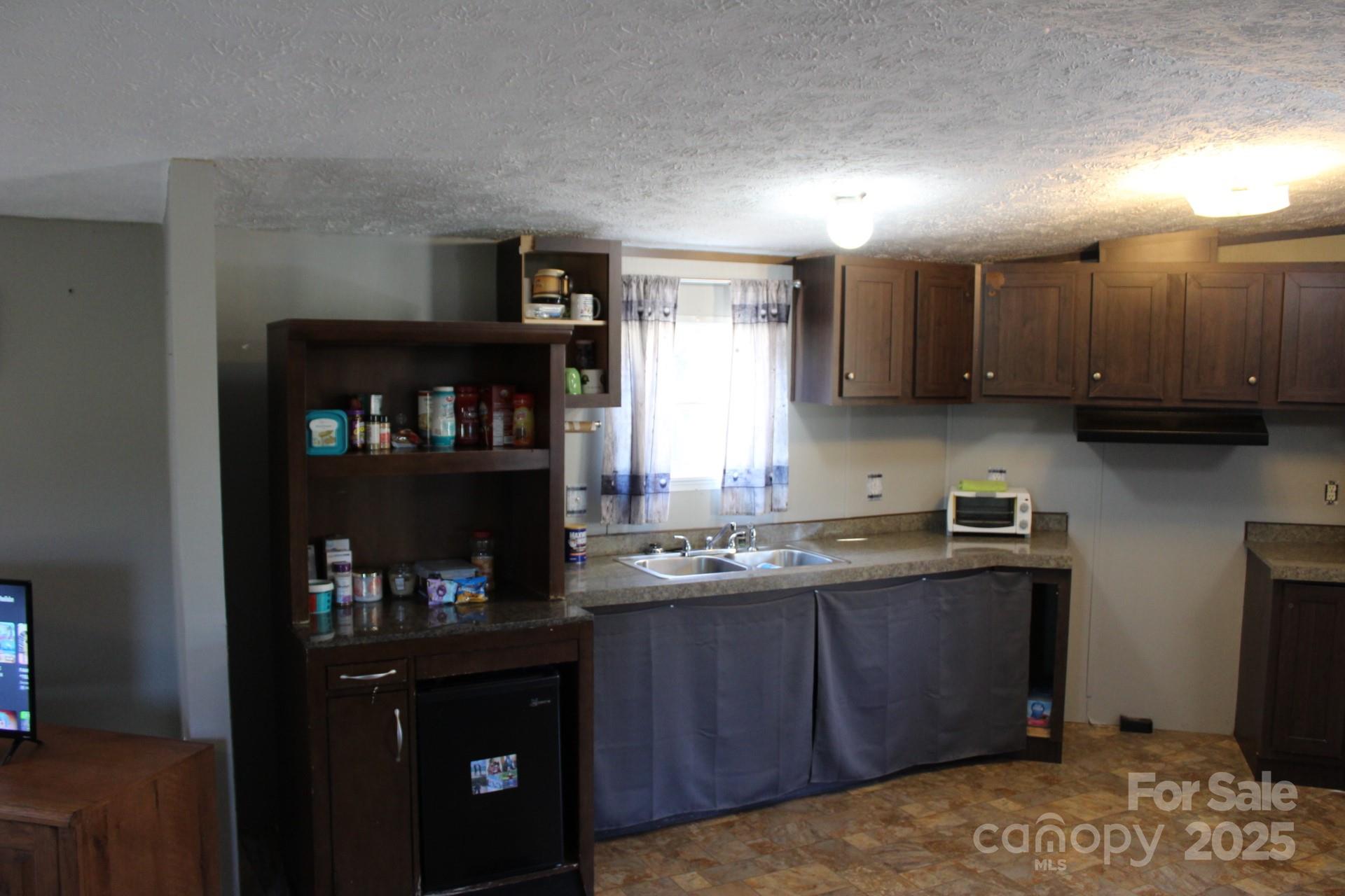 260 Buck Br Road Mill Spring, NC 28756 - Photo 18 of 32 a kitchen with stainless steel appliances granite countertop a refrigerator a sink dishwasher and wooden cabinets