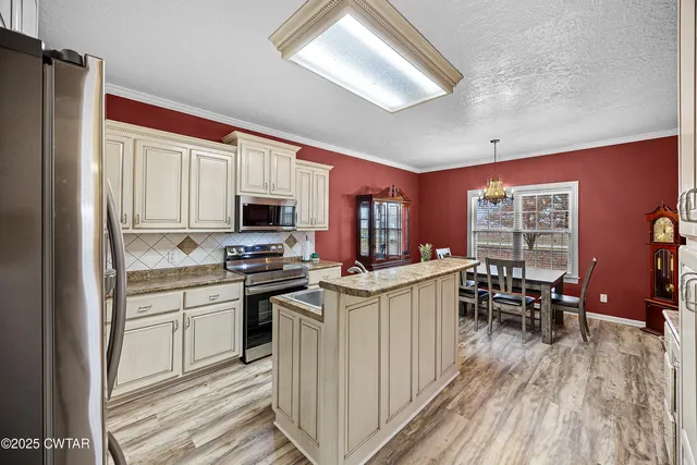 a kitchen with stainless steel appliances granite countertop a refrigerator a stove top oven a sink dishwasher and wooden cabinets with wooden floor