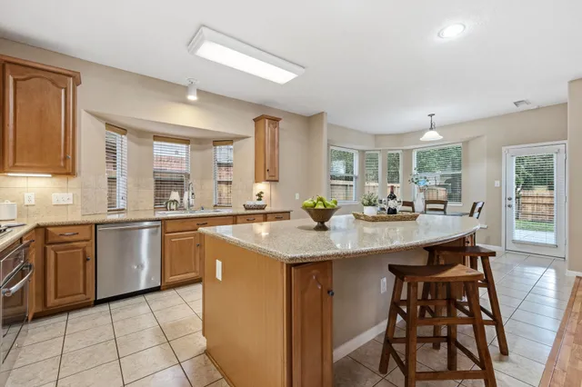 a kitchen with stainless steel appliances granite countertop table chairs sink and cabinets