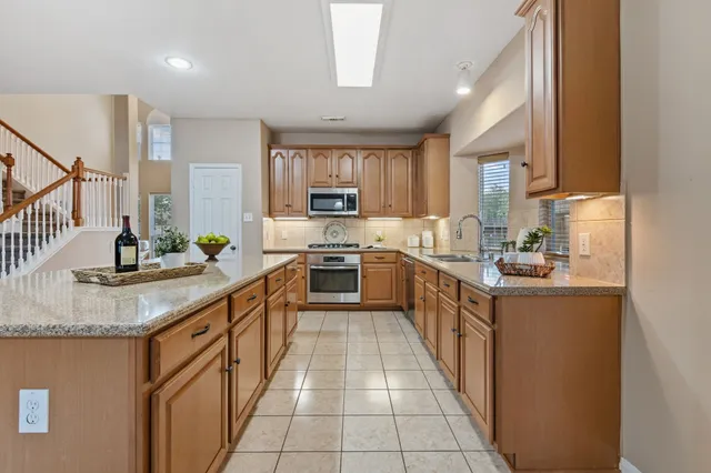 a kitchen with stainless steel appliances granite countertop a sink counter space cabinets and a large window