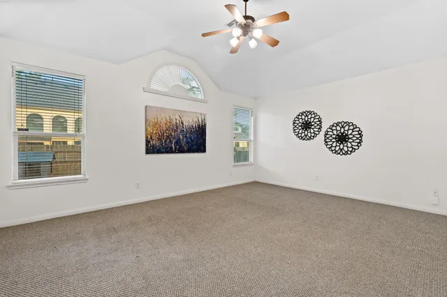 an empty room with windows and fan