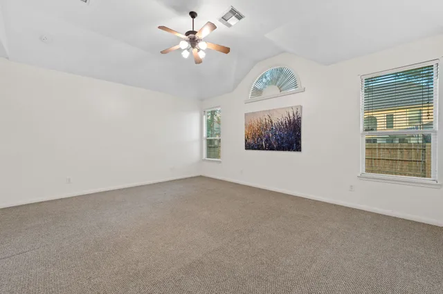 an empty room with windows and fan