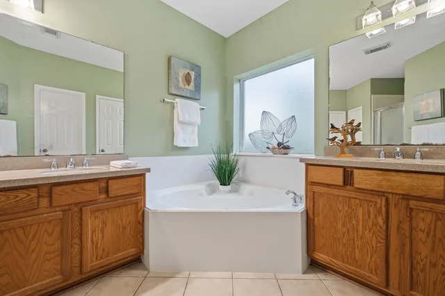 a bathroom with a sink vanity granite tub shower and a mirror