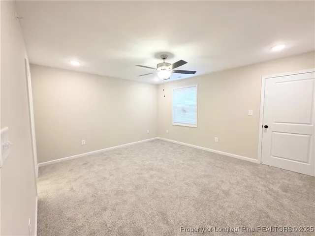 an empty room with a chandelier fan and windows