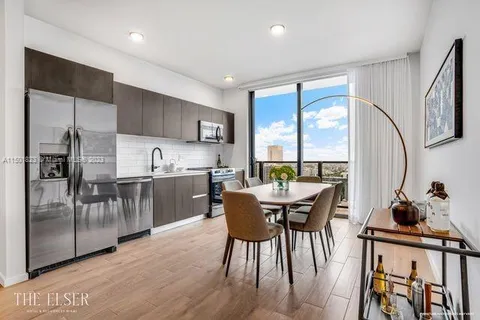 a kitchen with stainless steel appliances granite countertop a stove top oven a sink and a dining table with wooden floor