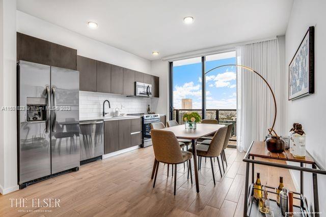 398 Northeast 5th Street, Unit 2804 Miami, FL 33132 - Photo 5 of 17 a kitchen with stainless steel appliances granite countertop a stove top oven a sink and a dining table with wooden floor