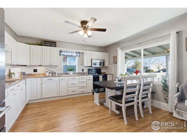 a kitchen with stainless steel appliances kitchen island granite countertop a dining table chairs and white cabinets