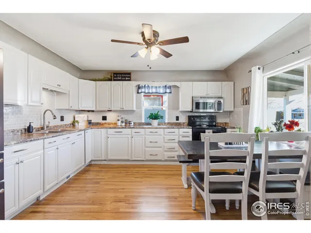 a kitchen with stainless steel appliances kitchen island granite countertop a refrigerator oven a sink dishwasher and white cabinets with wooden floor