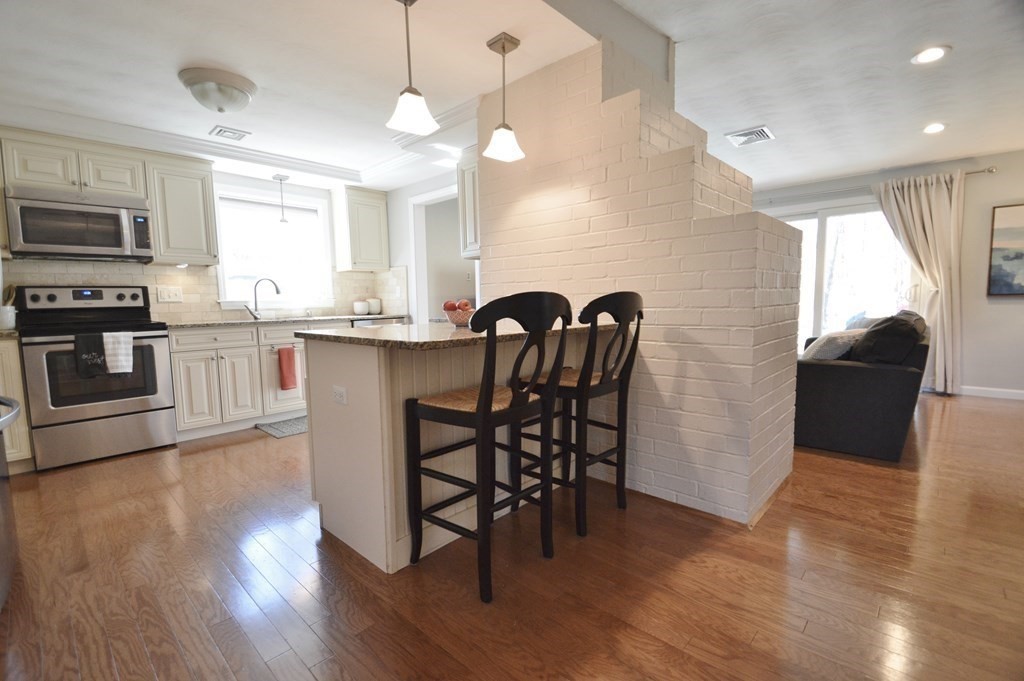 24 Raleigh Road Framingham, MA 01701 - Photo 2 of 37 a kitchen with stainless steel appliances granite countertop a stove top oven a sink a dining table and chairs with wooden floor