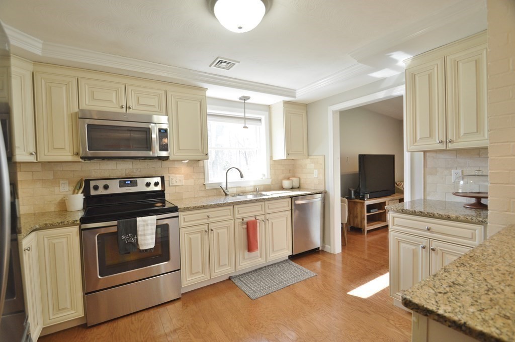 24 Raleigh Road Framingham, MA 01701 - Photo 6 of 37 a kitchen with stainless steel appliances granite countertop a stove top oven a sink dishwasher and a microwave oven with white cabinets
