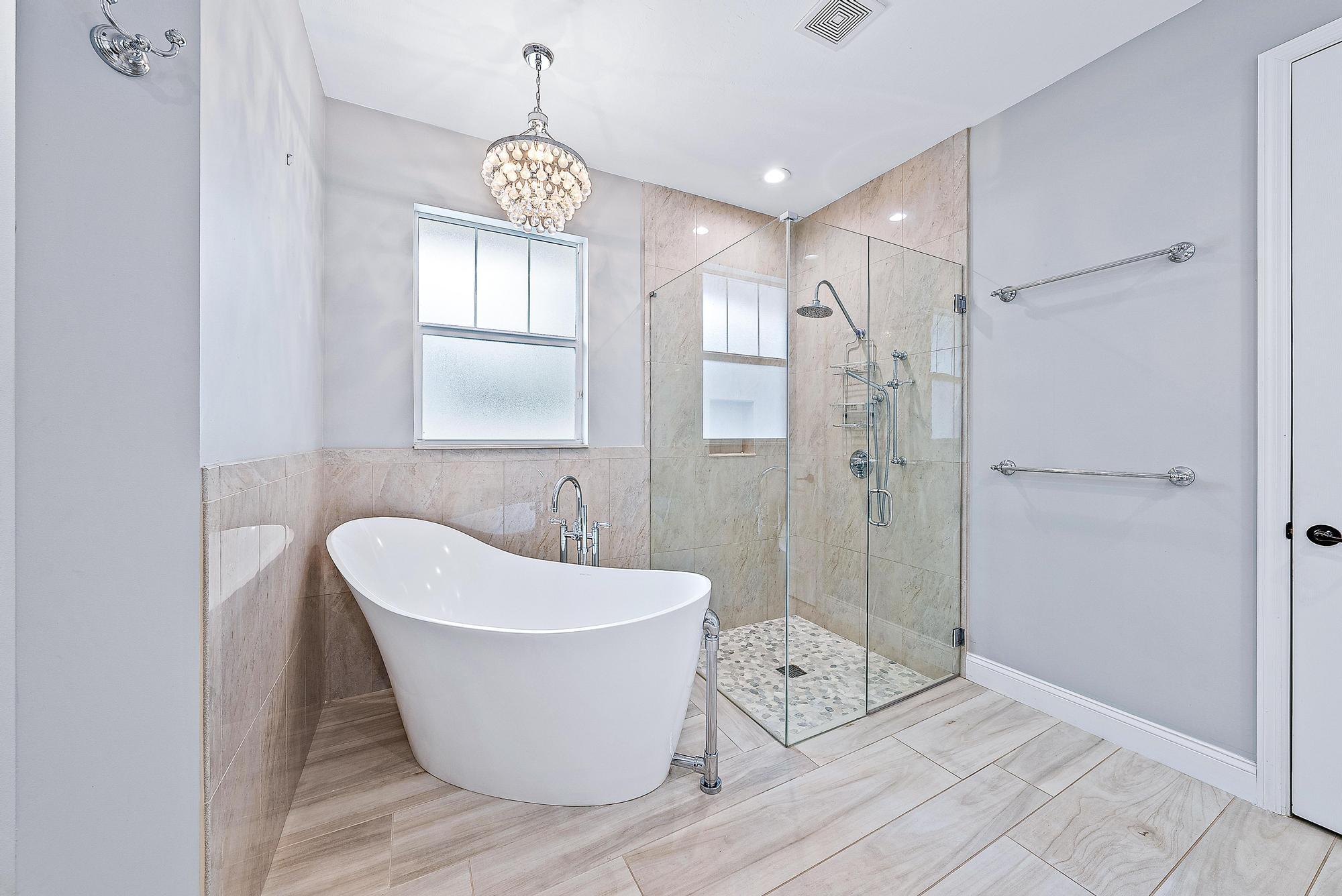 2702 West Mallory Boulevard Jupiter, FL 33458 - Photo 21 of 39 a white bath tub sitting in a bathroom and shower