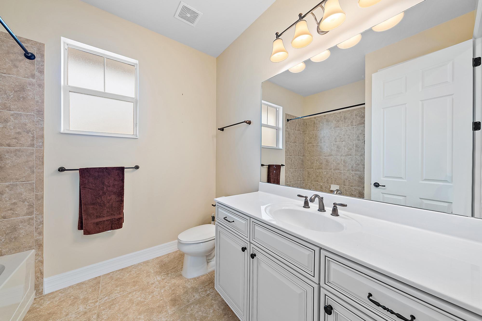 2702 West Mallory Boulevard Jupiter, FL 33458 - Photo 27 of 39 a bathroom with a toilet sink and mirror