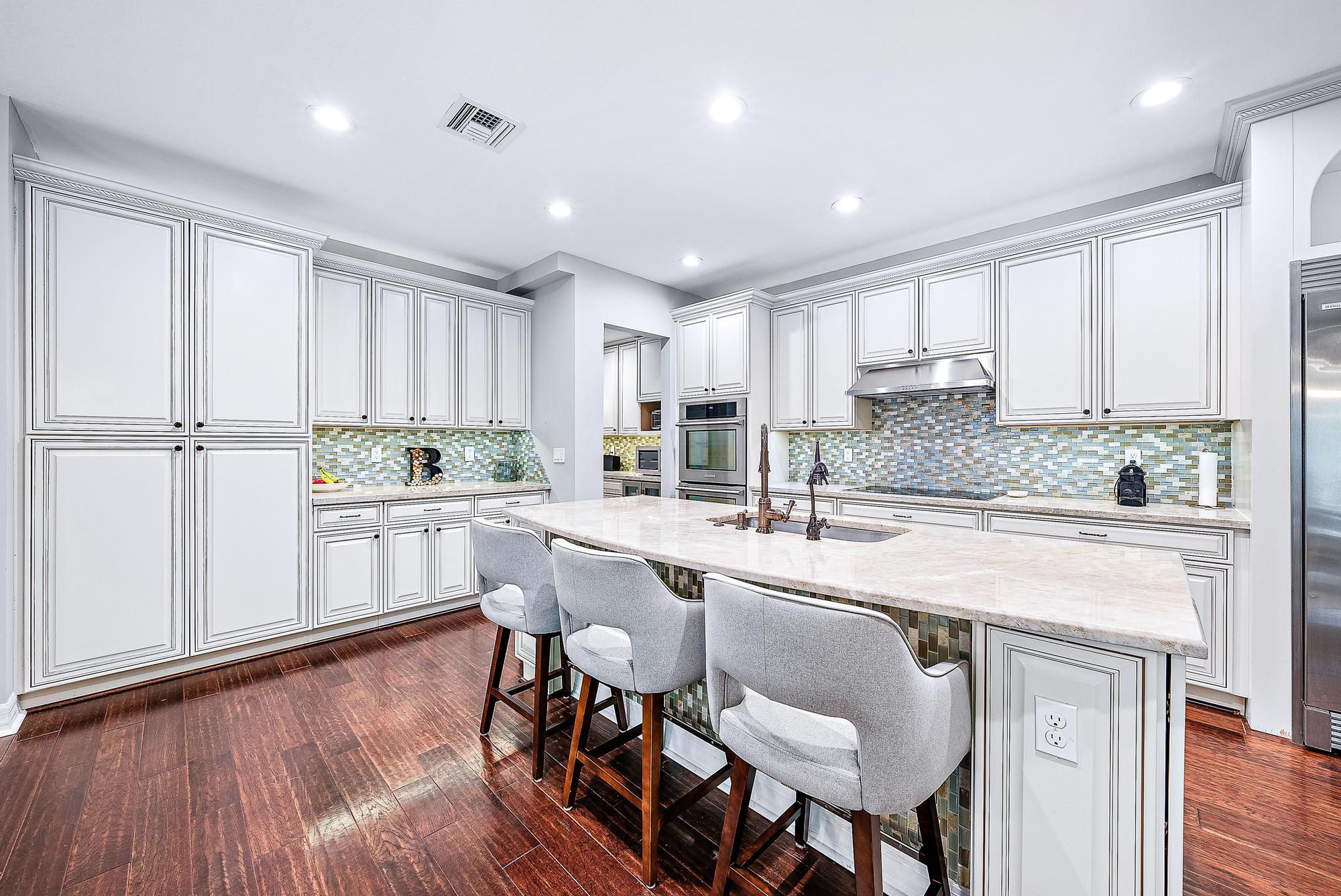 2702 West Mallory Boulevard Jupiter, FL 33458 - Photo 8 of 39 a kitchen with stainless steel appliances granite countertop a white cabinets and wooden floor