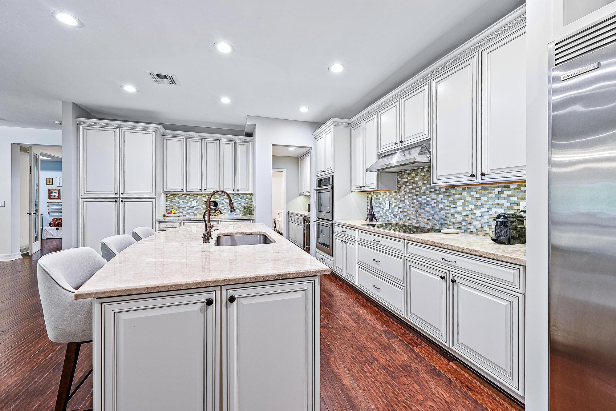 2702 West Mallory Boulevard Jupiter, FL 33458 - Photo 10 of 39 a kitchen with kitchen island granite countertop a sink cabinets and wooden floor