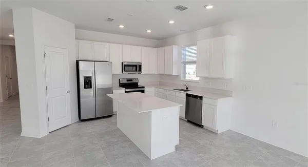 a kitchen with kitchen island a white cabinets and refrigerator