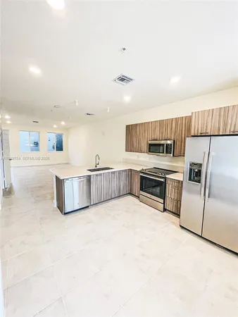 a large white kitchen with a stove a sink dishwasher and a refrigerator with wooden floor
