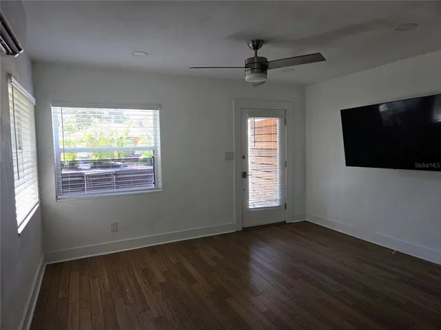 an empty room with wooden floor fan and windows