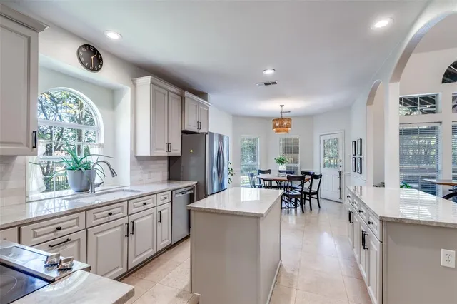 a large kitchen with kitchen island a large counter space a sink appliances and a large window