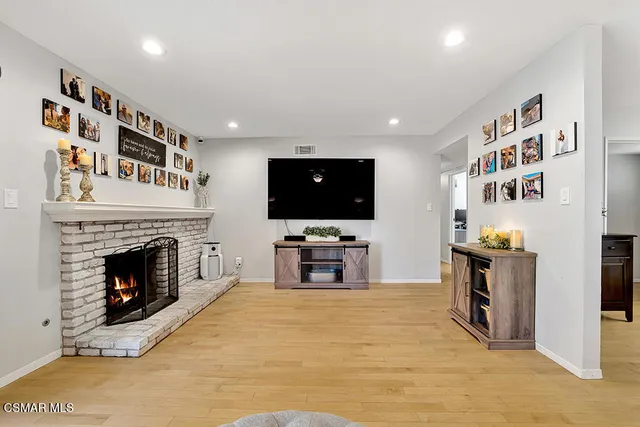 a living room with stainless steel appliances furniture a fireplace and a flat screen tv