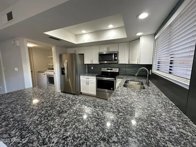 a kitchen with a sink a refrigerator a microwave a stove and cabinets