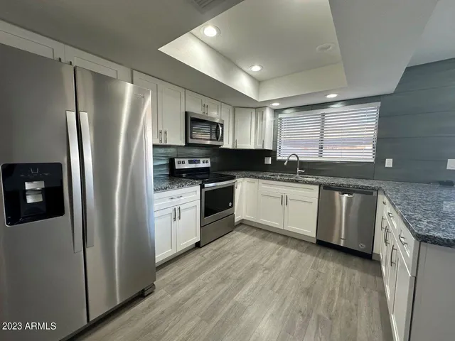 a kitchen with granite countertop a sink cabinets and wooden floor
