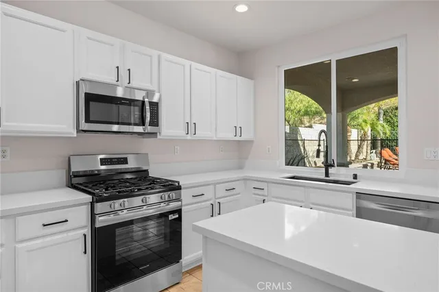 a kitchen with white cabinets and sink