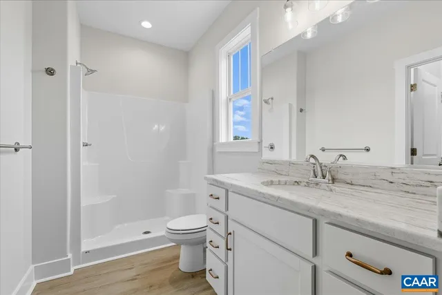 a bathroom with a granite countertop sink a toilet and shower