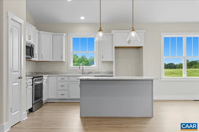 a kitchen with stainless steel appliances granite countertop a sink a stove a refrigerator and island with wooden floor