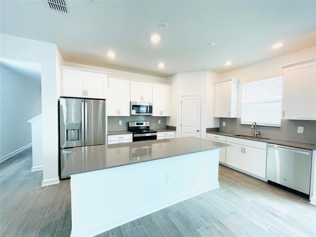 11732 Language Way Orlando, FL 32832 - Photo 6 of 24 a large kitchen with granite countertop a large counter top stainless steel appliances and cabinets