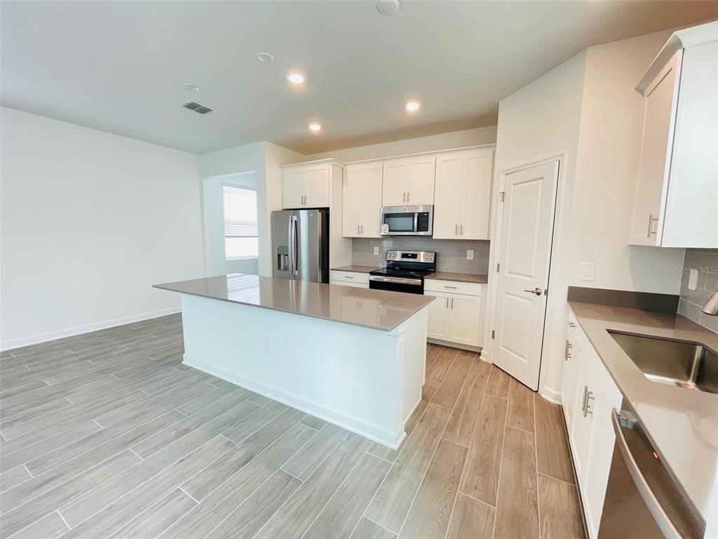 11732 Language Way Orlando, FL 32832 - Photo 7 of 24 a large kitchen with a center island wooden floor stainless steel appliances and cabinets