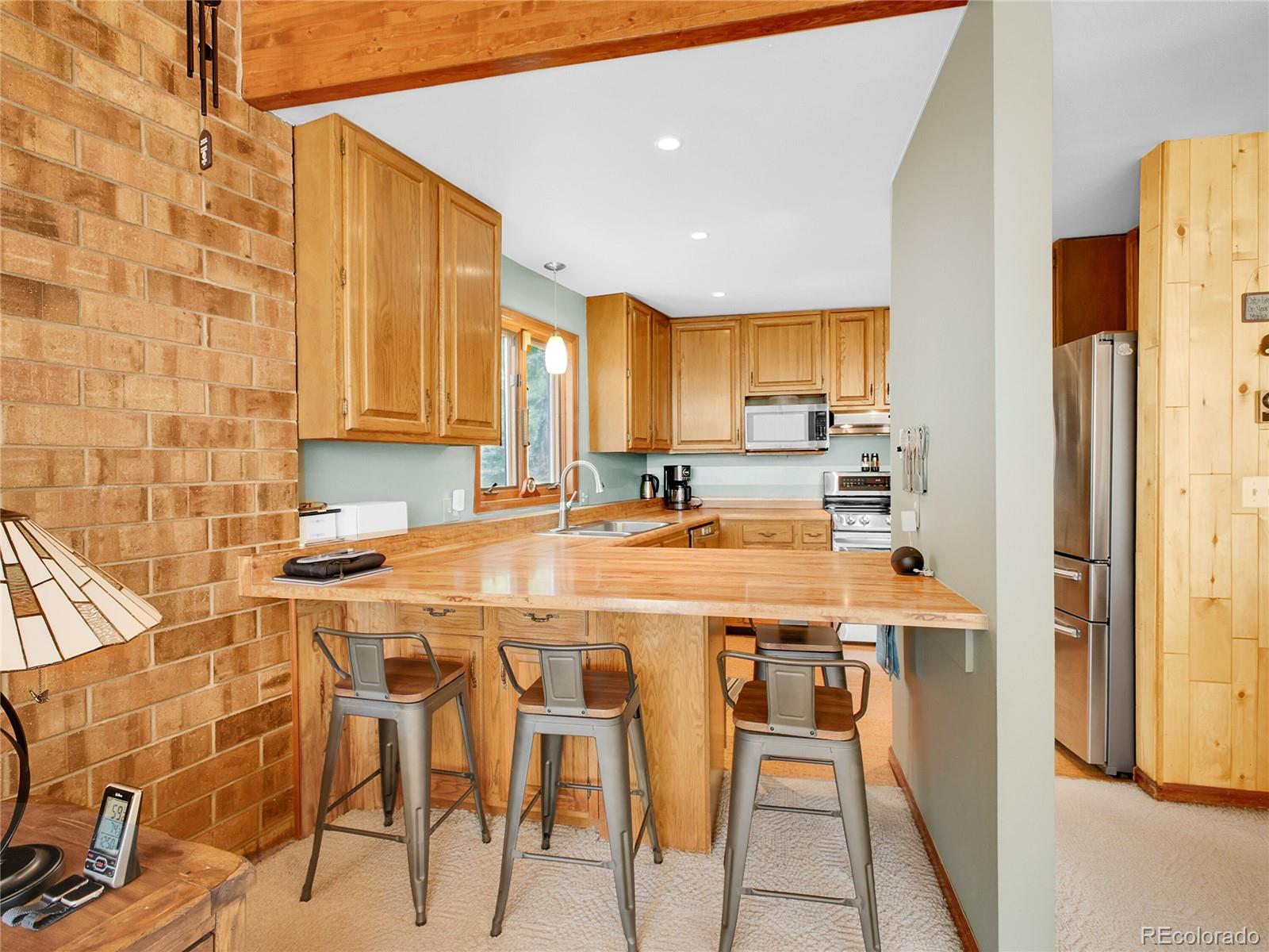 29752 Bearcat Trail Conifer, CO 80433 - Photo 11 of 50 a kitchen with stainless steel appliances kitchen island granite countertop a refrigerator a stove a sink and white cabinets with wooden floor