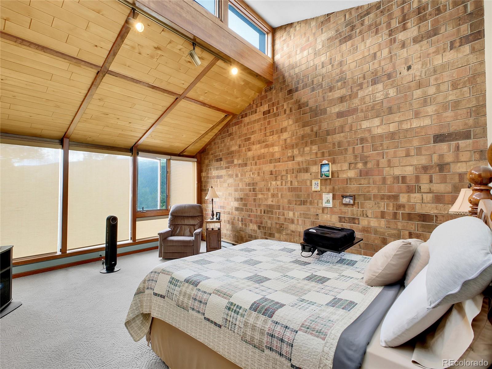 29752 Bearcat Trail Conifer, CO 80433 - Photo 29 of 50 a bedroom with a bed a couch and a window