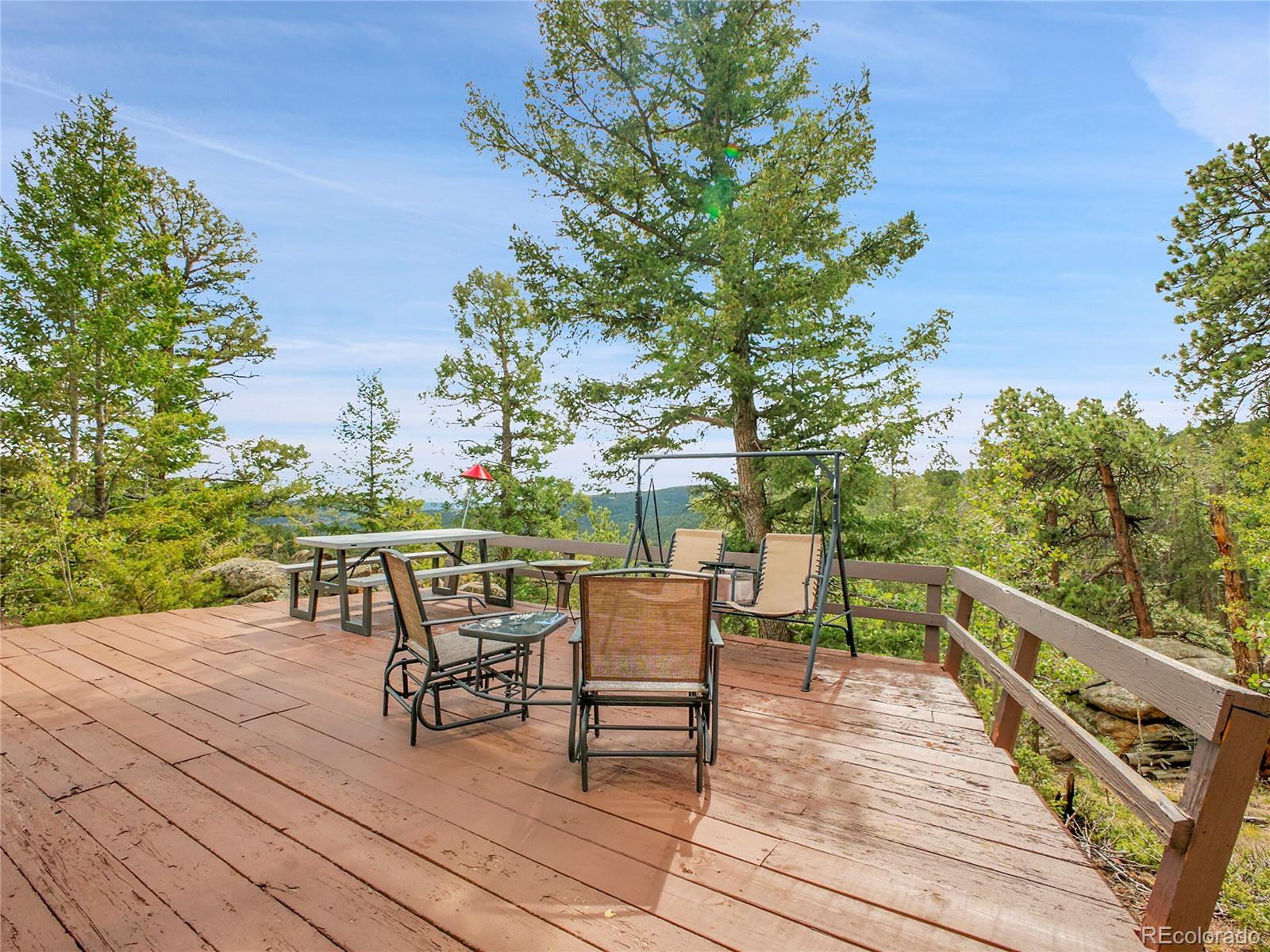 29752 Bearcat Trail Conifer, CO 80433 - Photo 4 of 50 a deck view with a table and chairs and wooden floor