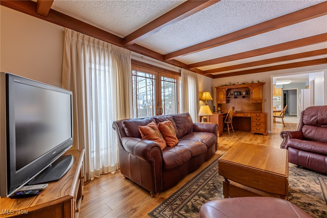 535 Barrington Ridge Road Painesville, OH 44077 - Photo 22 of 48 Living room featuring beam ceiling, light hardwood / wood-style flooring, and a textured ceiling
