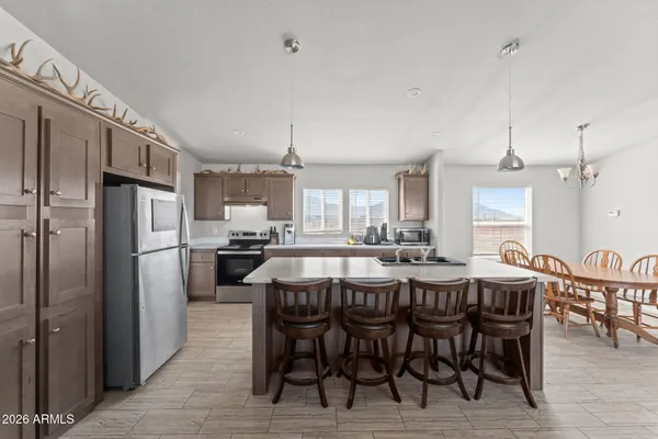 a kitchen with refrigerator a sink dining table and chairs
