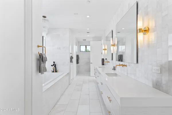 a spacious bathroom with a tub sink and mirror