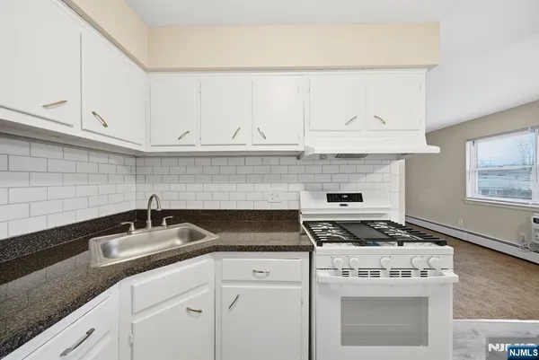 a kitchen with granite countertop a stove sink and cabinets