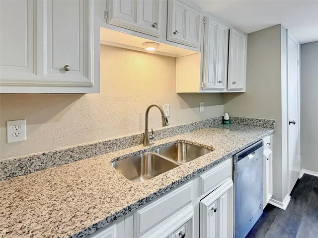 a kitchen with granite countertop white cabinets and sink
