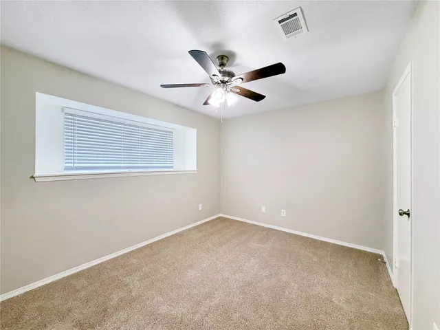 a view of an empty room with a ceiling fan and a window