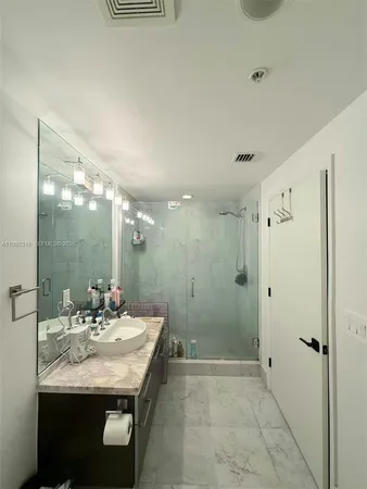 a bathroom with a granite countertop sink a mirror and a shower