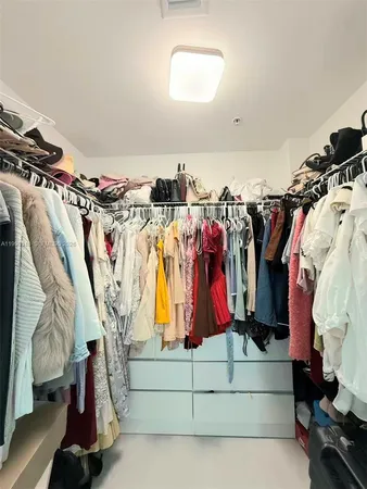 a view of walk in closet with clothes and shoes