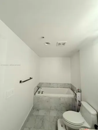 a bathroom with a granite countertop toilet and a bathtub